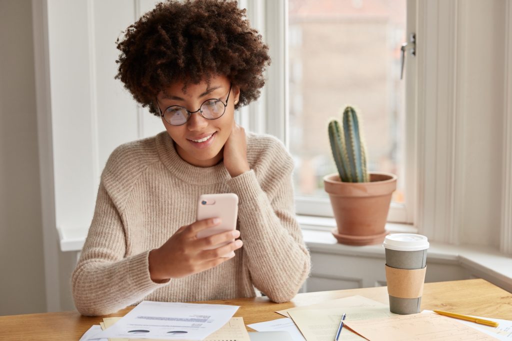 Positive owner of trading corporation holds modern smart phone, checks email box, waits for message